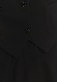 Černý přiléhavý blazer s klopami, dvouřadým zapínáním, texturovanou látkou a čtyřmi černými knoflíky pro zapínání.