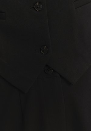 Zwarte op maat gemaakte blazer met een notch revers, dubbele sluiting, gestructureerde stof en vier zwarte knopen voor sluiting.