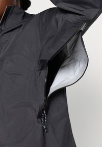 Giacca leggera nera con ventilazione laterale con zip, fodera interna liscia e regolazione con cordino all'orlo.