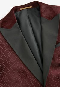 Sacou din catifea burgundy, cu model geometric embosat, revere din satin negru și căptușeală texturată. Textură moale notabilă și design croit.