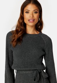 Dunkelgrauer gerippter Strickpullover mit langen Ärmeln, rundem Ausschnitt und gebundenem Taillenelement. Verfügt über ein strukturiertes Muster und eine figurbetonte Silhouette.