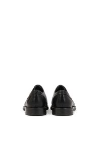 Scarpe in pelle nera con punta arrotondata e finitura liscia. Il design presenta un tacco basso e dettagli di cucitura minimi sul retro.