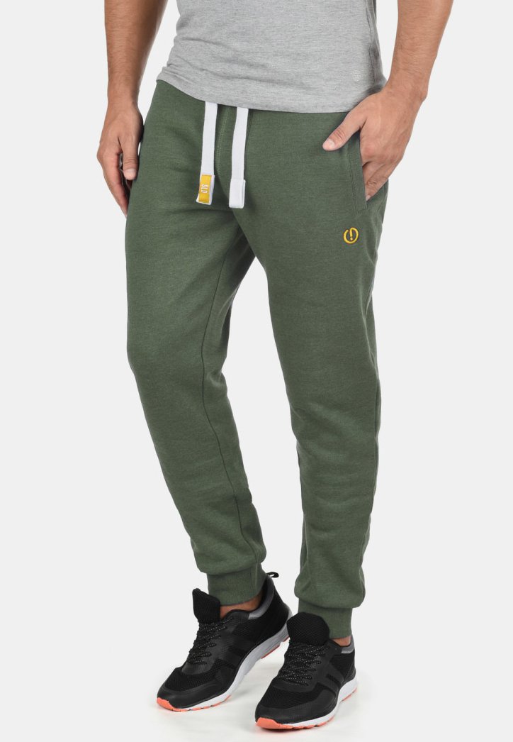 Green sweatpants made of soft fabric, featuring a relaxed fit, white drawstring, and a small yellow logo on the thigh.