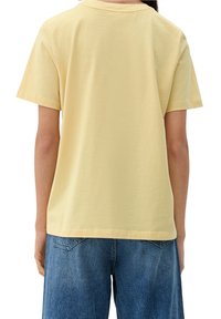 Camiseta de algodón amarilla de manga corta con cuello redondo, que presenta un ajuste relajado y corte recto. La vista posterior muestra un diseño simple, sin detalles adicionales.