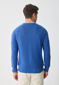 Königsblauer gestrickter Pullover mit gerippten Bündchen und Saum. Verfügt über einen runden Halsausschnitt und ein strukturiertes Stichmuster, das minimale sichtbare Nähte zeigt.