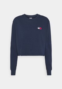 Tummansininen lyhyt sweatshirt pehmeästä kankaasta, jossa on pitkät hihat. Vasemmassa rinnassa on pieni monivärinen "TOMMY JEANS" -logokirjailu.
