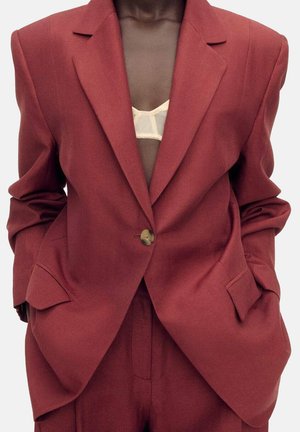 Maroon oversized blazer i texturerat tyg med vadderade axlar och en enkel knappstängning, med två framfickor.