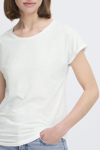 Īsām piedurknēm, apaļa kakla baltā t-kreklu, izgatavots no gludas kokvilnas auduma. Iezīmes rullētas piedurknes un brīva piegriezuma, ieslīpēts zilajos džinsos.