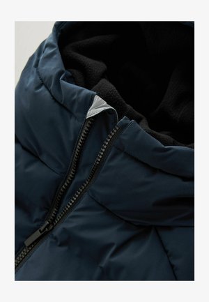 Granatowa kurtka puchowa z miękkim polarowym podszyciem, metalowym zamkiem błyskawicznym oraz wysokim kołnierzem z szarym akcentem przy otwarciu.