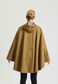 Beżowy kapturek z lekkiego, gładkiego materiału; ma luźny krój z szerokimi rękawami oraz prosty, schludny design.