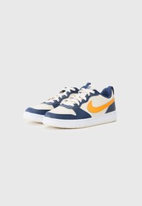 Baskets de sport avec un schéma de couleurs crème, marine et orange. Présente un dessus en cuir lisse, une semelle en caoutchouc et un design à lacets.