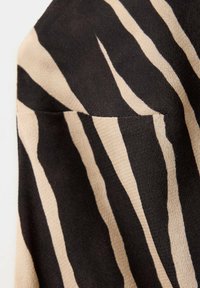 Black and beige zebra-striped fabric with a small, sewn-in pocket detail.