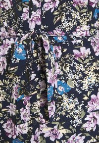 Robe florale avec un fond navy, ornée de motifs roses, bleus et verts, un devant à boutons et une ceinture à nouer pour accentuer la taille.