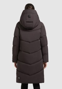 Abrigo acolchado marrón oscuro con capucha, presenta un acolchado en forma de chevron y un detalle de botón en el cuello. Incluye una etiqueta con el logo en el dobladillo.