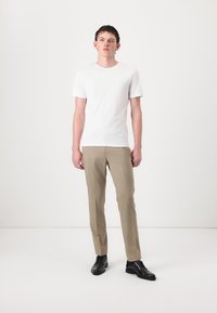 White short-sleeve t-shirt paired with beige tailored trousers and black lace-up shoes. The outfit has a clean and minimalist design.