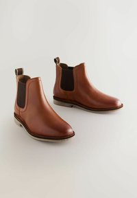 Stivali Chelsea in pelle marrone con pannelli laterali elasticizzati, punta arrotondata e suola texture. Presentano un occhiello sul retro per facilitarne l'uso.