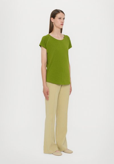 Green short-sleeve top paired with beige flared pants. The top has a round neckline and a relaxed fit, made from a soft-textured fabric.
