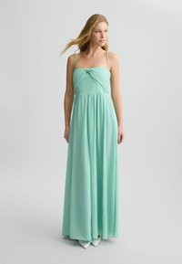 Abito maxi verde menta con scollatura a nodo, spalline sottili e gonna fluida realizzata in tessuto leggero. Presenta un design semplice.