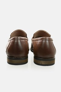Mocasines de cuero marrón con un acabado suave, punta redondeada y tacón bajo apilado. Presentan costuras sutiles y una suela de contraste.