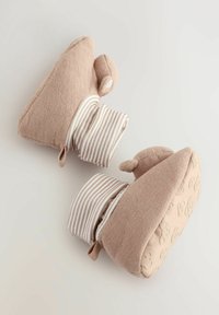 Mjuk beige tygstövlar med en strukturerad sula, randig manschett och björngesiktsdetaljer på undersidan. Rund tådesign.