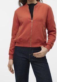 Veste bomber rouge avec fermeture éclair, poignets et ourlet côtelés ; deux poches avant zippées ; tissu doux avec une texture lisse.