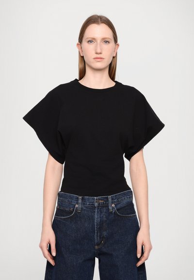 Tricou negru cu mânecă scurtă și un design larg, structurat. Materialul pare moale, cu o textură netedă. Asortat cu blugi din denim albastru cu talie înaltă.