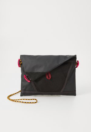 Czarna torba z tkaniny z siatkowym panelem, kontrastującym różowym okuwaniem i żółto-czarnym plecionym paskiem. Prostokątny kształt z klapą zamykającą.