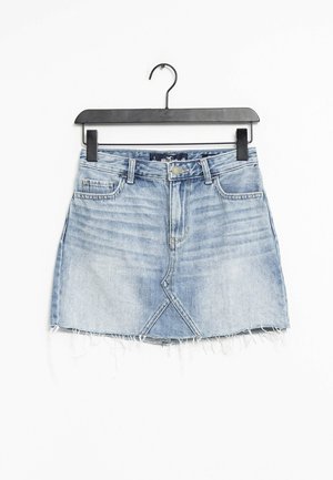 Jasnoniebieska spódniczka mini z wyblakłego denimu z postrzępionym dołem, przednimi kieszeniami, szlufkami na pasek i trójkątnym przeszyciem z przodu, zawieszona na czarnym wieszaku.