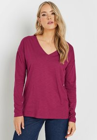 Langärmliges, V-Ausschnitt-Oberteil in tiefem Magenta, aus weichem Stoff mit lockerer Passform. Einfaches Design ohne Muster oder Verzierungen.
