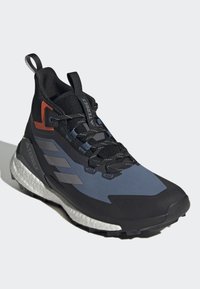 Czarno-niebieskie buty trekkingowe z siateczkową cholewką, teksturowanymi akcentami, pomarańczowymi detalami oraz solidną gumową podeszwą z segmentowaną białą bieżnią.