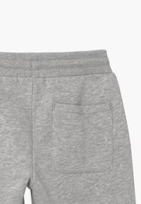 Grå mjukisbyxor med elastiskt midjeband och en enda bakfickor, tillverkade av mjukt, melerat tyg.