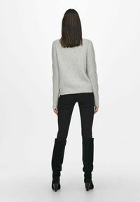 Gray ribbed sweater with long sleeves, paired with black skinny jeans and knee-high black boots featuring pointed heels.