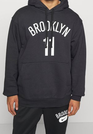 Sudadera negra con capucha con "BROOKLYN" y el número "11" en blanco, combinada con pantalones negros con "BROOKLYN" y un logo blanco de Nike.