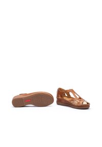 Scarpe con tacco a cuneo in pelle marrone con design a intaglio, dettagli metallici, suola testurizzata e cucitura intrecciata lungo il bordo.