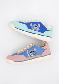 Deux baskets colorées avec le personnage Stitch et le logo, l’une en bleu et menthe, l’autre en bleu, rose et beige, sur fond blanc.