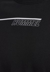 Sort ribbet kortærmet skjorte med et hvidt "HUMMEL" logo og en tynd vandret hvid stribe på tværs af brystet. Glat tekstur.