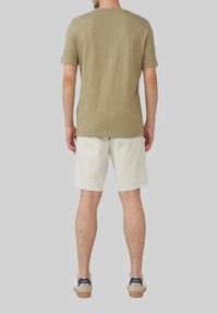 Oliwkowa koszulka z krótkim rękawem i białe szorty, w zestawie z białymi trampkami z granatowymi akcentami, prezentujące swobodny strój.