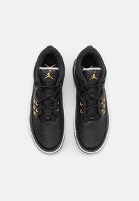 Baskets en cuir noir avec des accents dorés, surface perforée, bout rond et semelle blanche plate. Elles présentent un design à lacets et un col rembourré.