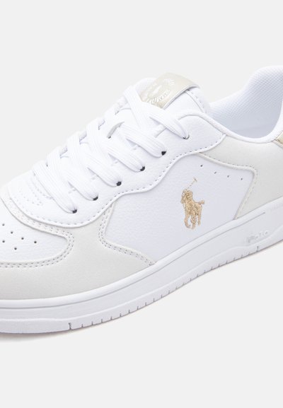 Λευκό δερμάτινο αθλητικό παπούτσι με λευκά κορδόνια, διάτρητη μύτη, χρυσό λογότυπο Polo Ralph Lauren στο πλάι και ανάγλυφη σόλα από καουτσούκ.