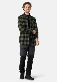 Groen en zwart geruit flanellen overhemd, met knoopsluiting en lange mouwen. Draagt over een zwart shirt en gecombineerd met grijze cargoshorts en zwarte broeken.