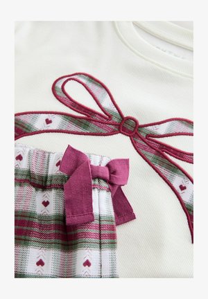 Fehér felső bordó hímzett szalagmintával. Alatta fehér, zöld és bordó mintás nadrág, amelyhez illő masni díszítés.