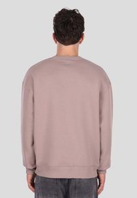 Svetlo vijolična jopa, z okroglim izrezom, rebrastimi manšetami in robom, mehke teksture, z majhno logosko značko na hrbtni strani. Tkanina, odporna proti tvorbi žmirk.