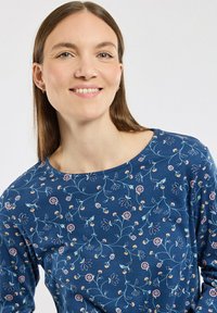 Haut à manches longues bleu à motifs floraux, avec un col rond, des motifs floraux de couleur claire et un tissu doux et texturé.