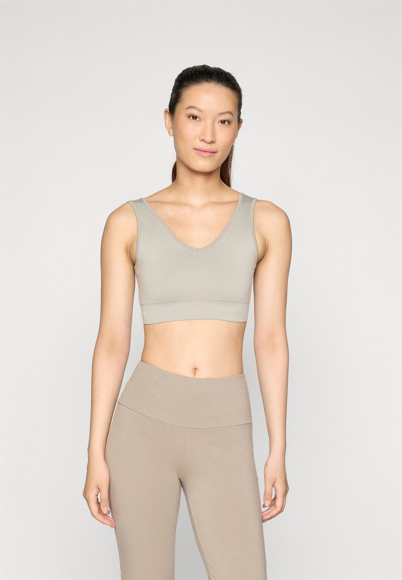 Brassiere gris con escote en V y tela suave y elástica. Combinado con leggings de cintura alta en un tono similar. Diseño simple.