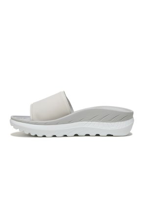 White slide sandals with a matte finish, flat sole, and textured grip details on the footbed for comfort and support.