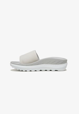 White slide sandals with a matte finish, flat sole, and textured grip details on the footbed for comfort and support.