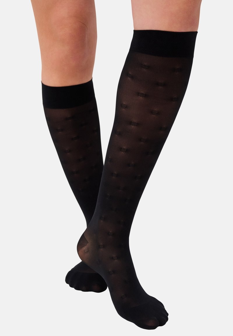Schwarze knielange Socken mit einem transparenten Finish und gepunktetem Muster. Der obere Rand ist einfarbig schwarz und sorgt für einen engen Sitz am Waden.