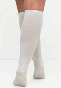 Calcetines de canalé hasta la rodilla en gris claro, hechos de una suave y elástica tela; cuentan con una puntera lisa y reforzada y un ajuste ceñido en la pantorrilla.