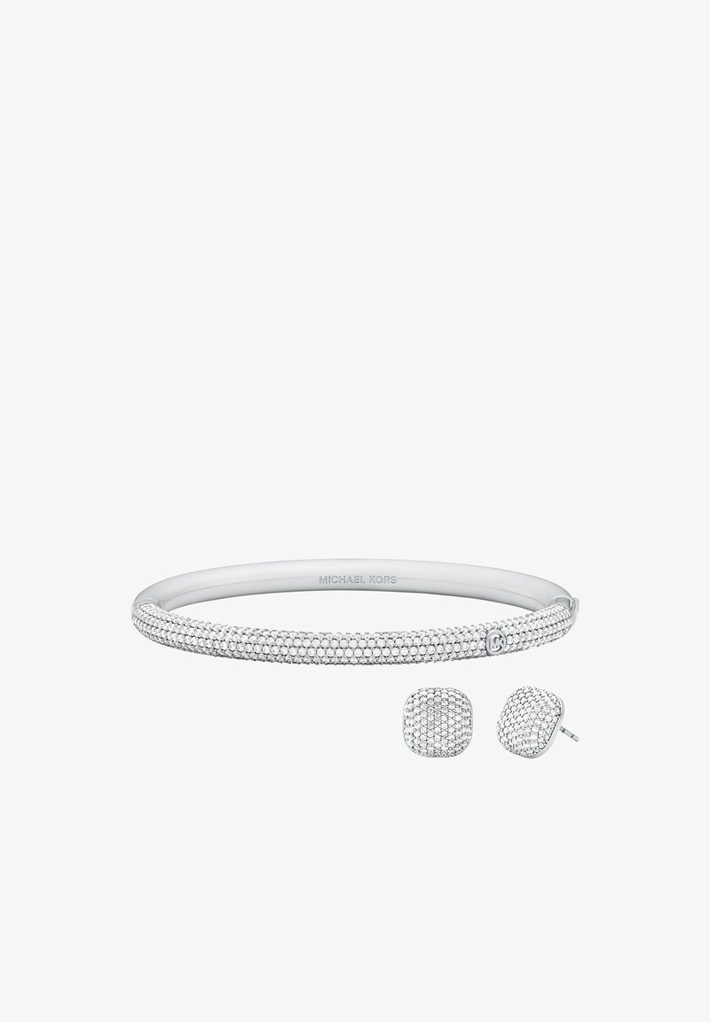 Pulsera de tono plateado de Michael Kors y pendientes de botón cuadrados a juego, incrustados con cristales, mostrados sobre un fondo blanco.
