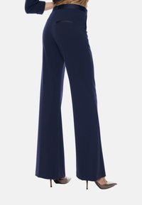 Pantaloni a gamba larga in navy realizzati in tessuto liscio, con una tasca posteriore e una cintura elegante. Abbinati a tacchi a punta.